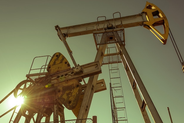 Photo oil pump rig operation on the platform in oil and gas industry. pumpjack, industrial equipment. oilfield site, oil pump are running. rocking machines for power genertion. petroleum concept. toned.