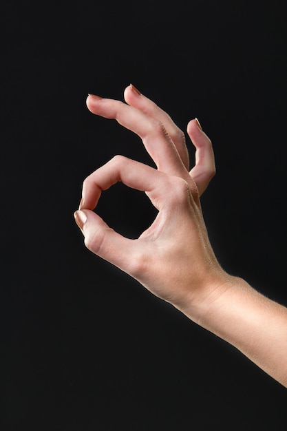 Ok gesture with hand on a isolated dark background