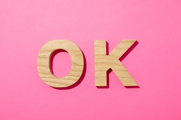 OK word made from wooden letters on pink background