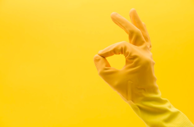 Okay hand gesture made by a hand in a yellow rubber cleaning glove