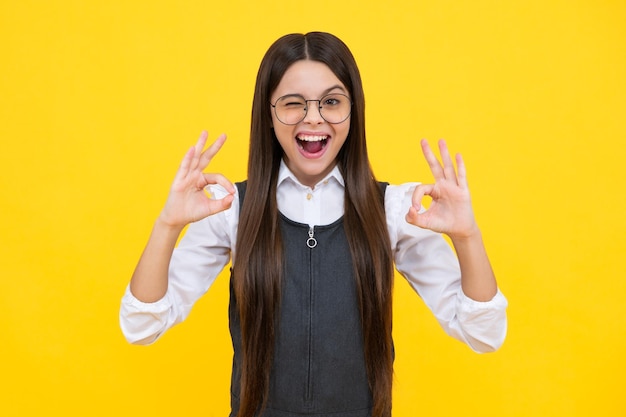 Okay Young girl child show fingers ok symbol sign language isolated on yellow background Funny