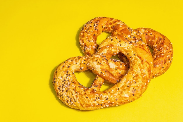 Oktoberfest concept - pretzels isolated on a yellow background. A trendy hard light, dark shadow, copy space