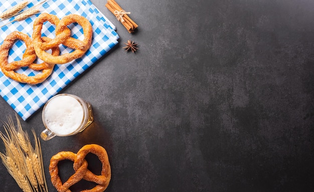 Oktoberfest festival decoration symbols made from Pretzel loaf beer and Bavarian white and blue fabric on dark stone background