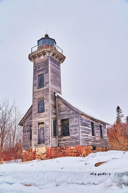 Old abandoned light house in winter on island during snow