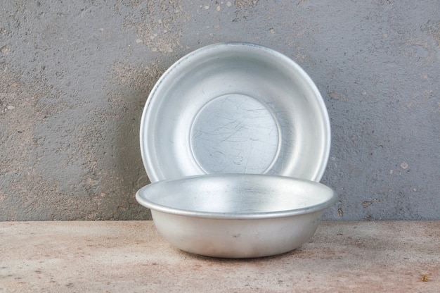 Old aluminum bowls on concrete background