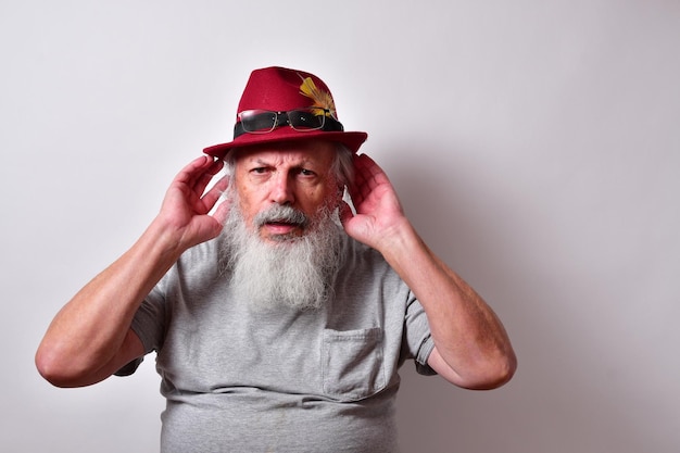 Old American male with grey shirt and red fedora hat indicating he can't hear