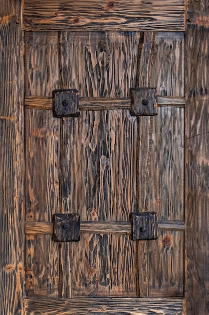 Old ancient antique door made of roughly hewn dark wood Abstract wooden background