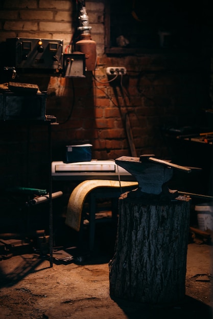 An old anvil attached to a wooden base stands in a private blacksmiths workshop.