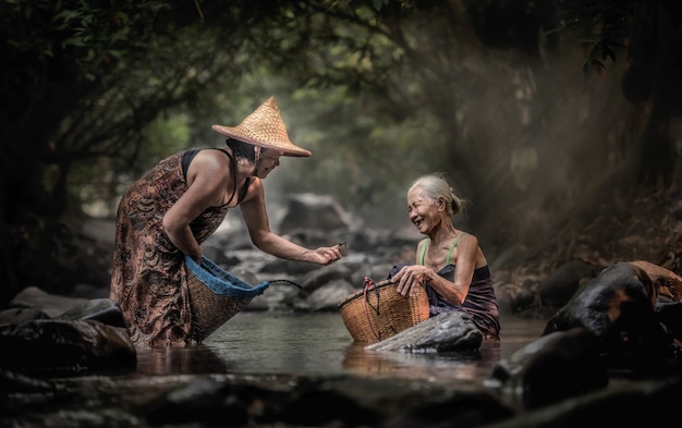 Old Asian woman working in cascade, Thailand