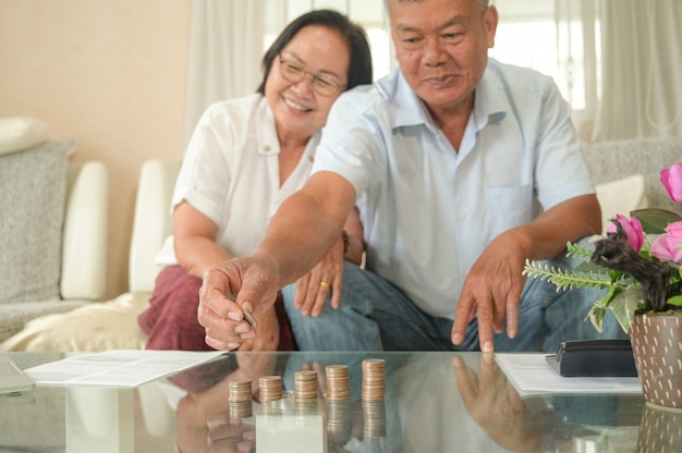 Old asian women and men sit on the sofa, they make financial plans.