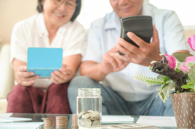 Old asian women and men sit on the sofa, they make financial plans.