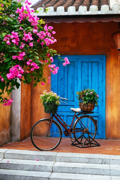 An old Bicycle with flowers in a basket on the background of an old wall .Garden home decoration.an old Bicycle against the wall in the garden.Vietnam