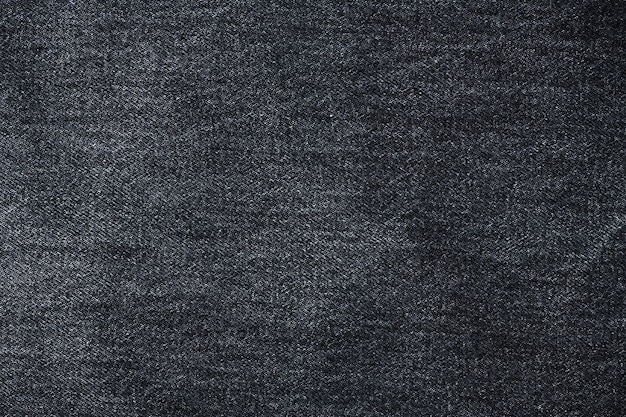 Old black jeans fabric background texture. Close up view.