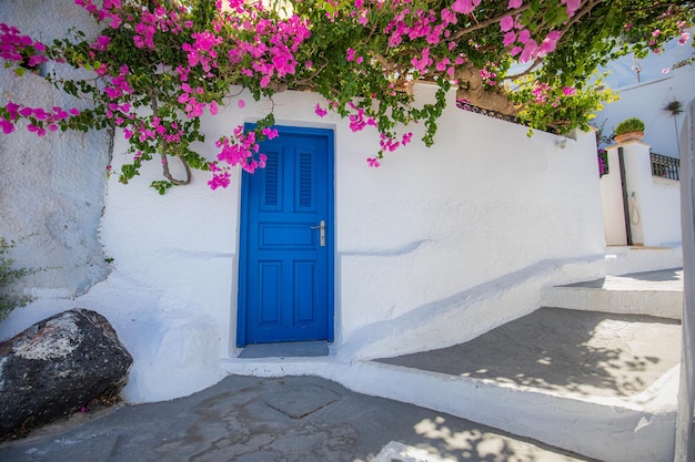 Old blue door and pink flowers, traditional Greek architecture, Santorini island, Greece. Romantic