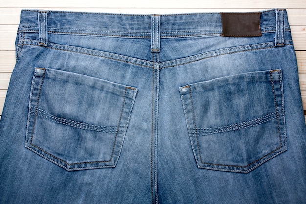 Old blue jeans - detail, a rear view of a wooden background