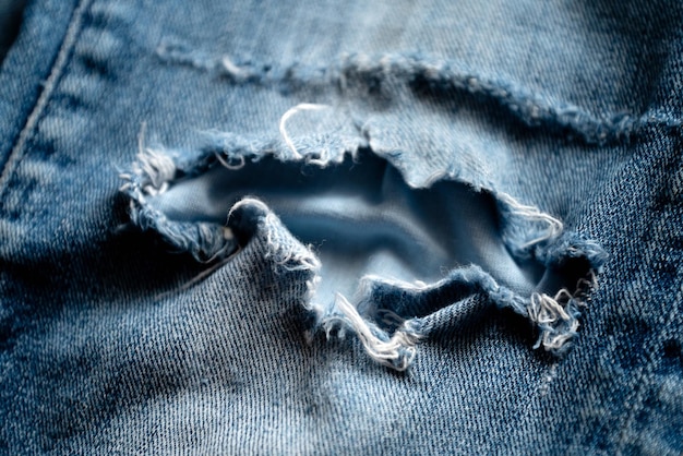 Old blue jeans torn at the knee close up