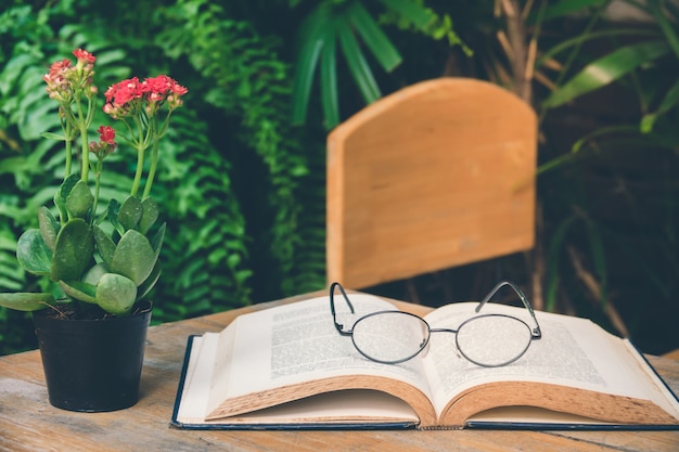 Old book open on table with reading glasses in garden