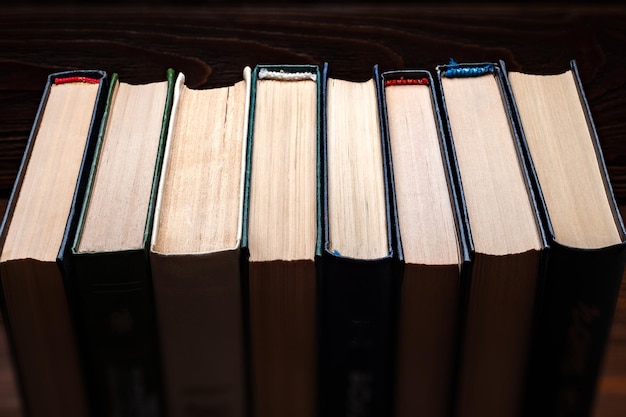 Old books A row of old used closed hardback books in dust on a dark wooden background