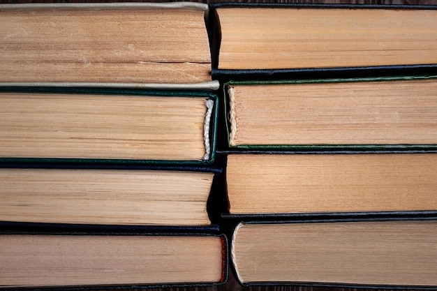 Old books Top view of old used closed hardback books in dust on dark wooden background