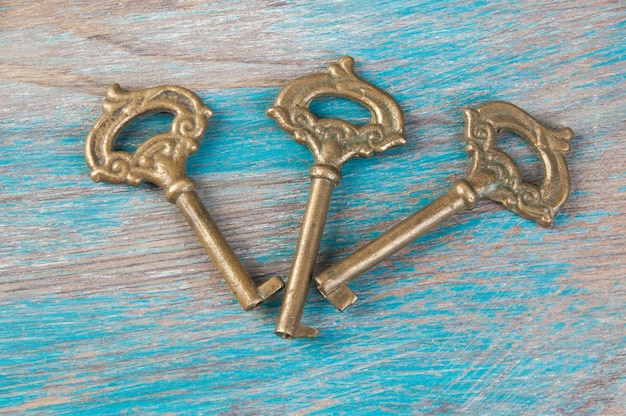 Old brass keys, detail of a classic metal keys on wooden background. Copy space for text`