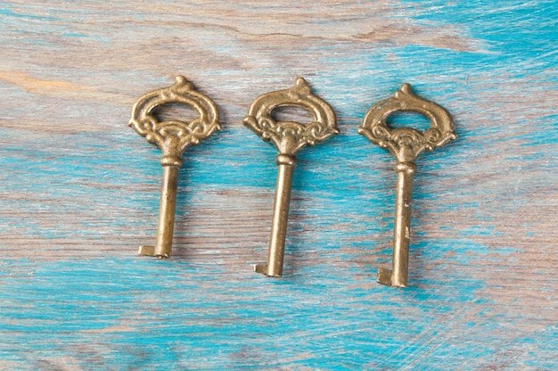 Old brass keys, detail of a classic metal keys on wooden background. Copy space for text`