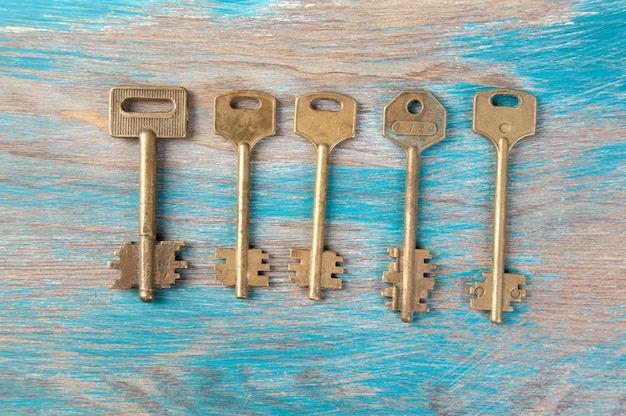 Old brass keys, detail of a classic metal keys on wooden background. Copy space for text