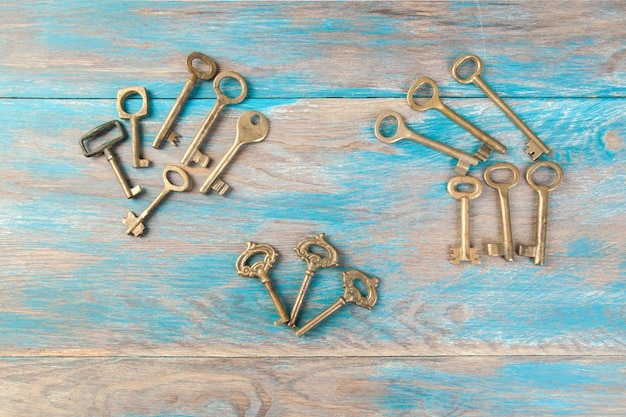 Old brass keys, detail of a classic metal keys on wooden background. Copy space for text`