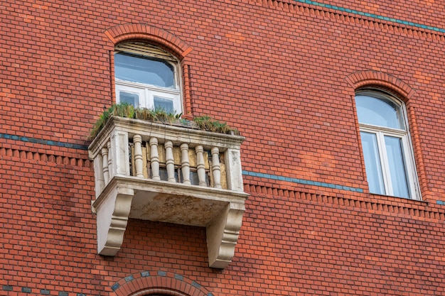 Old brick building wall with vintage windows and balcony