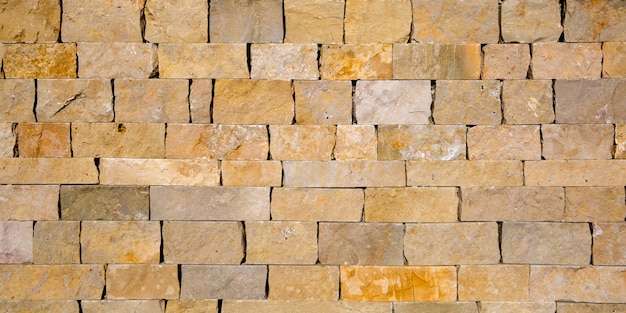 Old brick wall texture seamless background yellow natural sandstone tiles stitched together