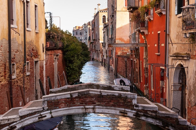 The old bridge made with red bricks on the typical canal in Venice