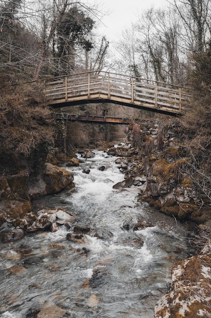 Old bridge in nature over river with rapid water and stones