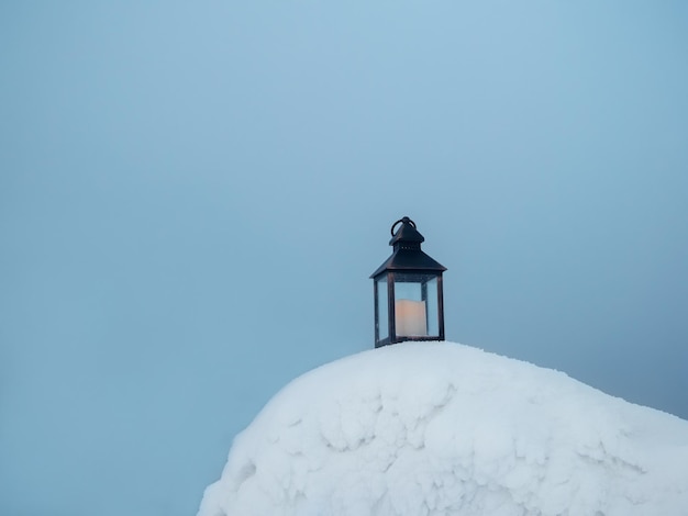 An old candle lantern stands on the evening snow in frosty winter