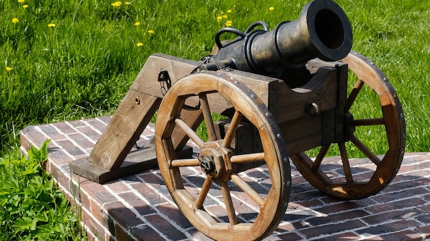 Old cannon with wooden wheels in the summer park