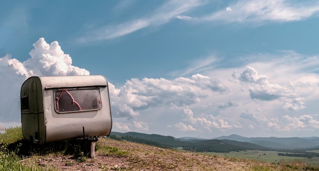 Old caravan abandoned on a hill against the sky colorful landscape mountain mobile home clouds sky c