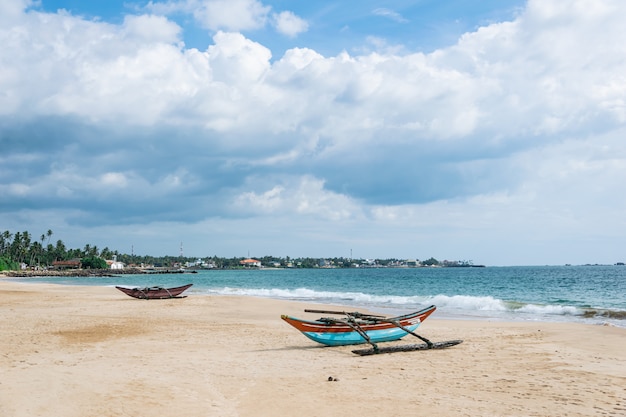 Old catamaran boats on the beach against the ocean and blue sky with beautiful clouds on a sunny day, Sri Lanka