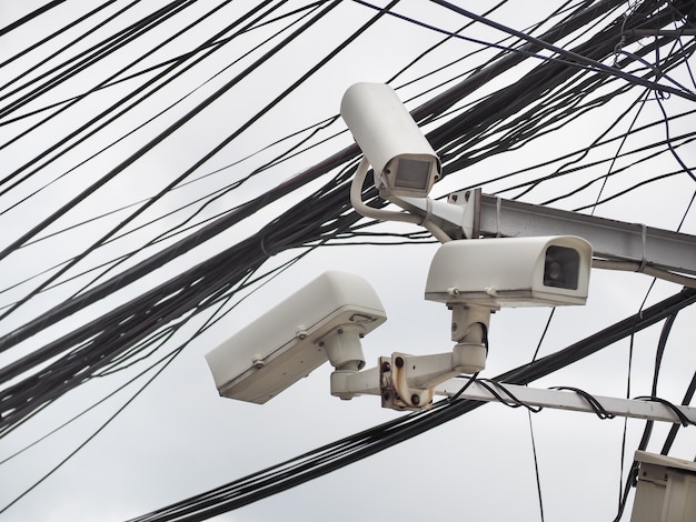 Old CCTV camera security hanging on chaos of cables and wire, Bangkok, Thailand