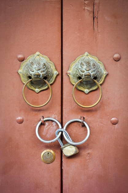 Old chinese lion doorknob and padlock on close brown wood door background