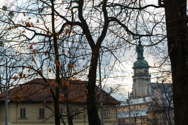 Old church tower in front of tree without leaves. autumn season.