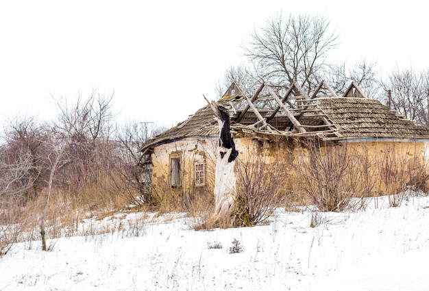 Old clay house in the Ukrainian village. Ruined clay house in the snow. 