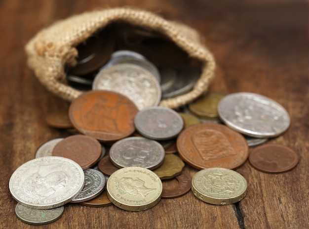 Old coins in sack bag on wooden surface