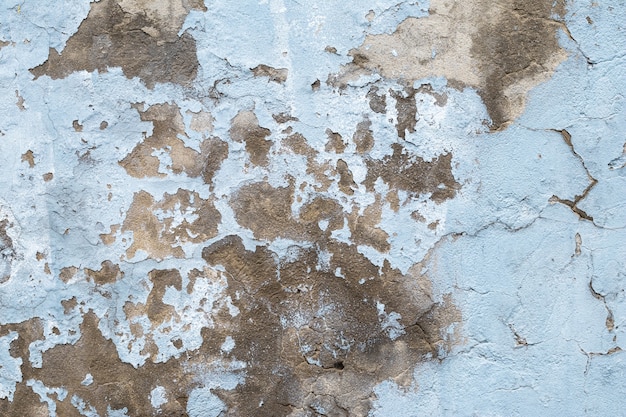 Old concrete wall with peeling paint. Close-up of blue ruined cement wall. Abstract grunge stucco texture. Cracked surface of plaster.