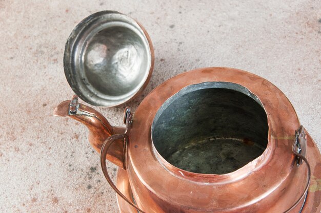 Old copper kettle on concrete background. Copy space for text, food photography props.