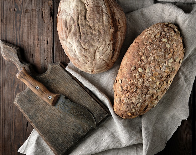 Old cutting board, knife and two loaves of brown bread