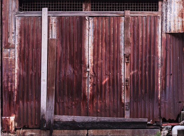 Old detailed aged vintage rusty corrugated red brown textured zinc alloy metal sheet exterior fence used in construction industry as a house building material.