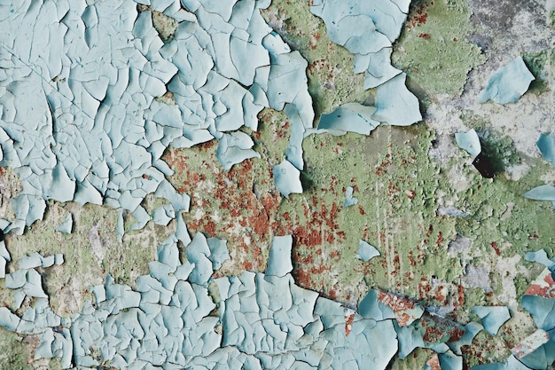 Old and dirty crumbling wall with peeling paint and cracks texture Grunge interior background closeup