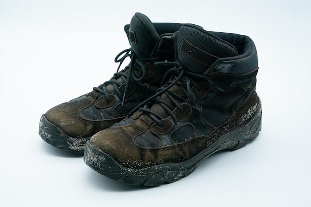 Old dirty sand and black work shoes with dirt on a white background