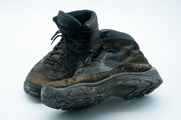 Old dirty sand and black work shoes with dirt on a white background