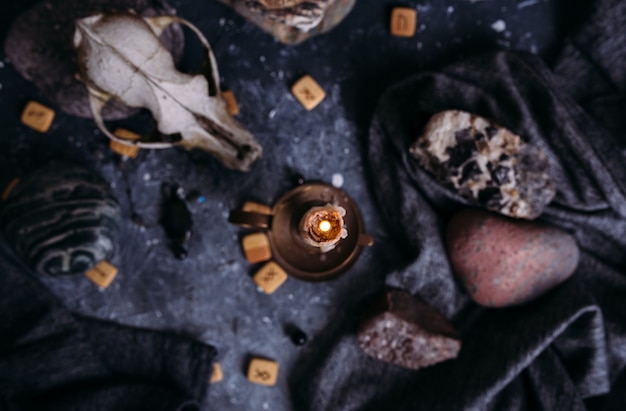 Photo old dog skull burning candle wooden runes and stones on the witch table