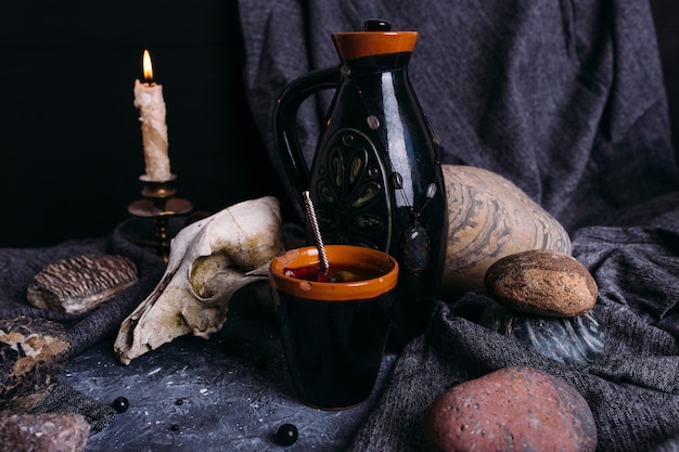 Old dog skull jug and stones on witch table enchanted drink with flower petals