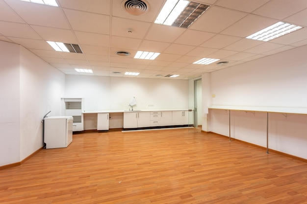 Old empty room with white kitchen furniture and sink that used to serve as office canteen for